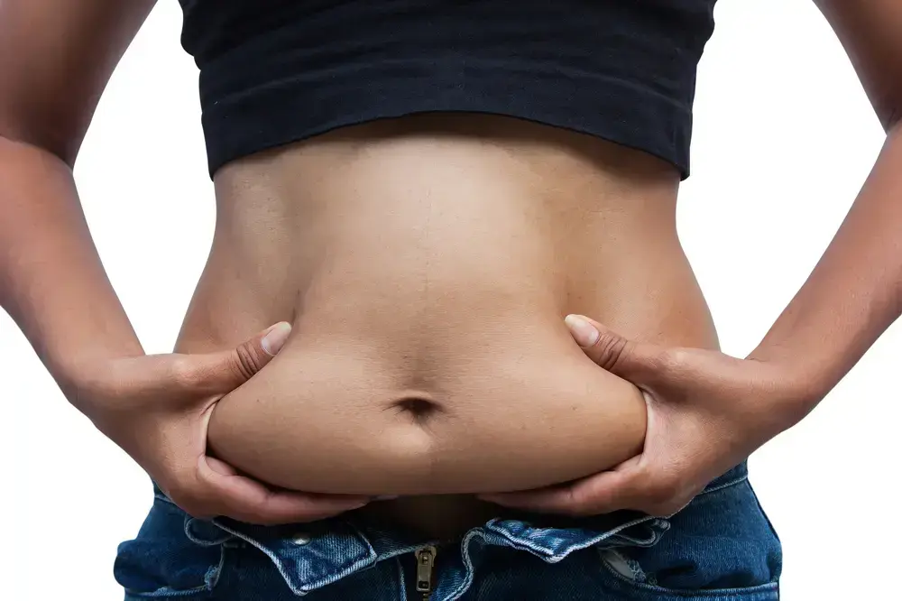 אישה מנסה לסגור ג'ינס על בטן שמנה (ShutterStock)
