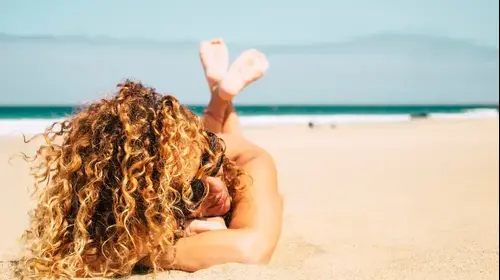 בחורה צעירה מתולתלת על חוף הים (ShutterStock) בחורה צעירה מתולתלת על חוף הים (ShutterStock)