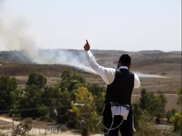 אדם ליד שריפה שנגרמה מנפילת רקטה באזור שדרות, מבצע "צוק איתן", יולי 2014 (רויטרס)