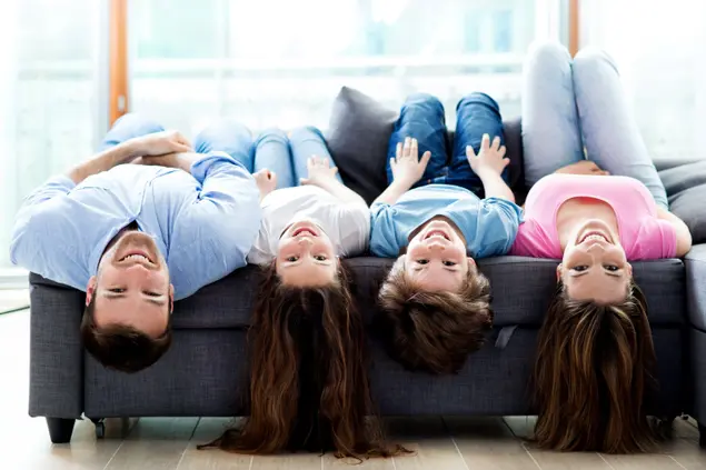 משפחה שוכבת הפוכה על ספה בבית (ShutterStock)