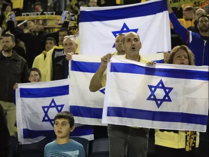 אוהדי בית"ר ירושלים עם דגלי ישראל ביציעים (מגד גוזני) אוהדי בית"ר ירושלים עם דגלי ישראל ביציעים (מגד גוזני)