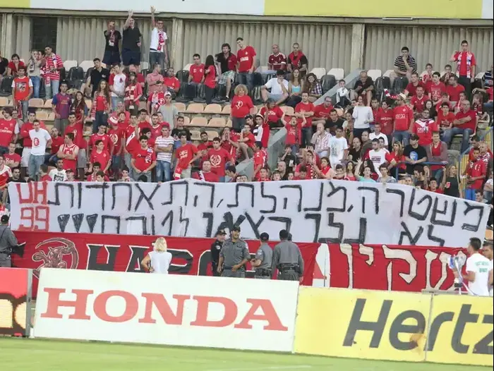 אוהדי הפועל תל אביב עם שלט מחאה (אדריאן הרבשטיין) אוהדי הפועל תל אביב עם שלט מחאה (אדריאן הרבשטיין)