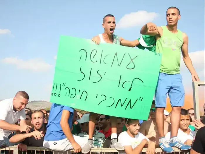 אוהדי מכבי חיפה עם שלט תמיכה בשחקן ויאם עמאשה (אדריאן הרבשטיין) אוהדי מכבי חיפה עם שלט תמיכה בשחקן ויאם עמאשה (אדריאן הרבשטיין)