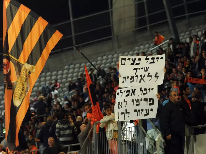 אוהדי בני יהודה מניפים שלטים נגד מאמן עכו יובל נעים (ברני ארדוב)