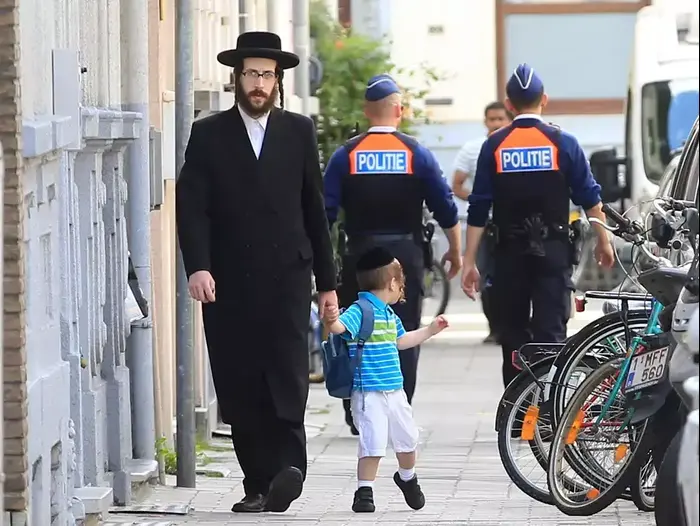 יהודי חרדי וילד עוברים שני שוטרים באנטוורפן, בלגיה, לאחר פיגוע במוזיאון יהודי בבריסל ביום שבת, מאי 25, 2014 (AP) יהודי חרדי וילד עוברים שני שוטרים באנטוורפן, בלגיה, לאחר פיגוע במוזיאון יהודי בבריסל ביום שבת, מאי 25, 2014 (AP)