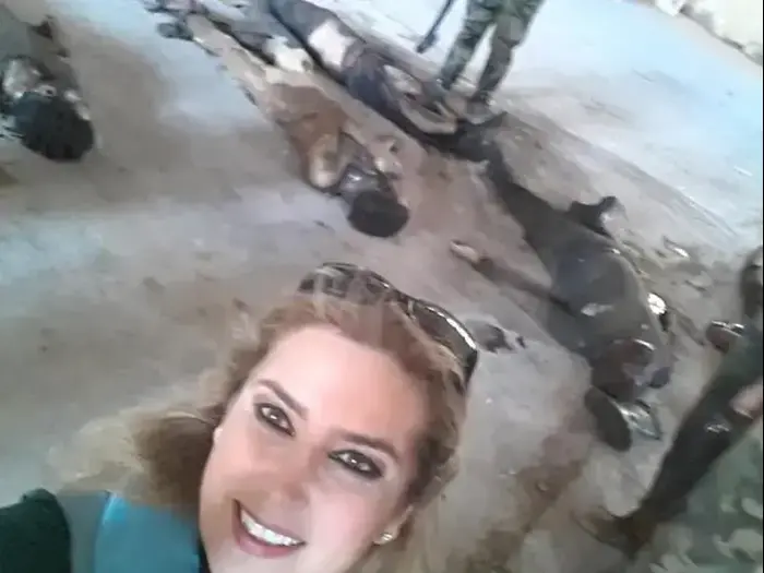 כנאנה עלוש, כתבת בערוץ טלוויזיה של משטר אסד מצטלמת על רקע גופות אזרחים שנהרגו במהלך הלחימה. יולי 2016 (צילום מסך , טוויטר) כנאנה עלוש, כתבת בערוץ טלוויזיה של משטר אסד מצטלמת על רקע גופות אזרחים שנהרגו במהלך הלחימה. יולי 2016 (צילום מסך , טוויטר)