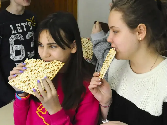 ויקי איגנטיוק (שמאל) וקייט קלויצ׳בסקי טועמים מצה שהובאה לכיתתם על ידי מתנדבים יהודים אשר מנסים להפריך סטריאוטיפים אנטישמיים הרווחים בקרב רבים במולדובה (לארי לקסנר) (אתר רשמי , לארי לקסנר) ויקי איגנטיוק (שמאל) וקייט קלויצ׳בסקי טועמים מצה שהובאה לכיתתם על ידי מתנדבים יהודים אשר מנסים להפריך סטריאוטיפים אנטישמיים הרווחים בקרב רבים במולדובה (לארי לקסנר) (אתר רשמי , לארי לקסנר)