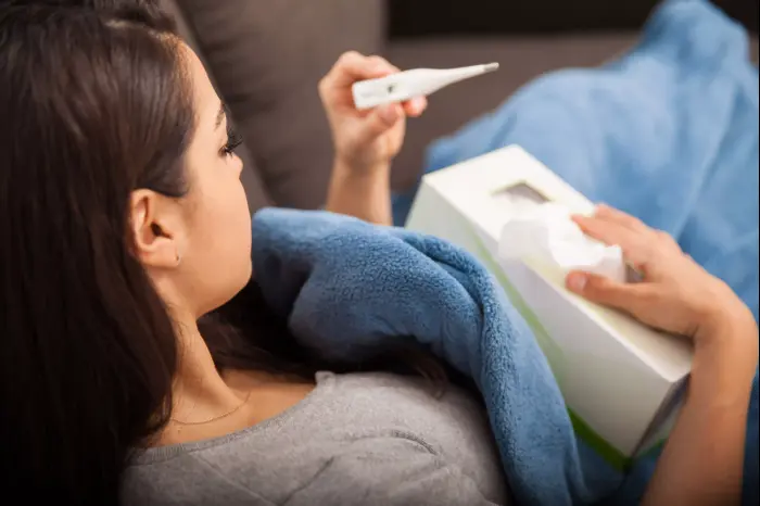 אישה חולה מחזיקה מדחום (ShutterStock) אישה חולה מחזיקה מדחום (ShutterStock)