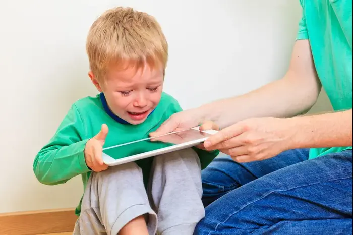 הורה לוקח טאבלט מידיו של ילד (ShutterStock)
