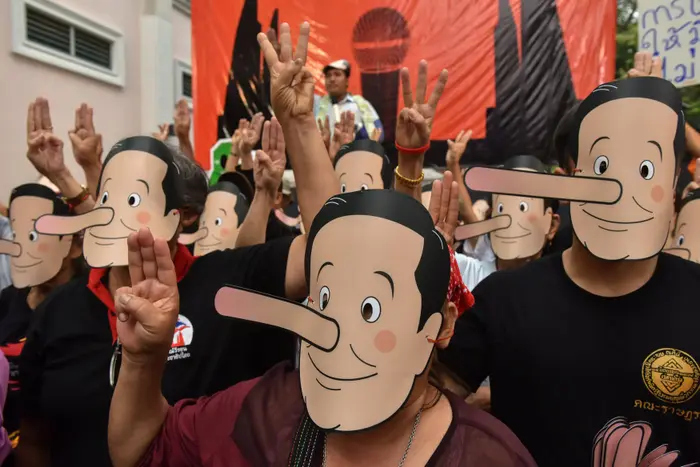 פעילי פרו-דמוקרטיה לבושים מסכות פינקוי כלעג על ראש ממשלת תאילנד פריות צ'אן אוצ'ה במהלך הפגנה באוניברסיטה בבנגקוק 24 בפברואר 2018 (רויטרס)