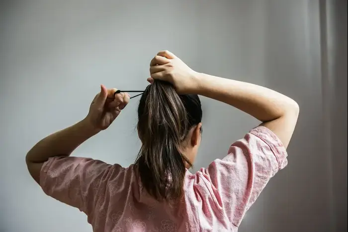 אישה אוספת את שיערה לקוקו (ShutterStock) אישה אוספת את שיערה לקוקו (ShutterStock)