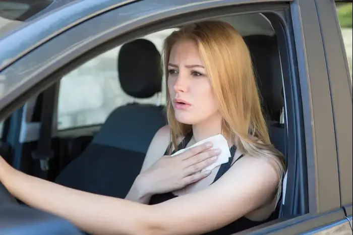 אישה נוהגת במכונית ומנגבת זיעה (ShutterStock) אישה נוהגת במכונית ומנגבת זיעה (ShutterStock)