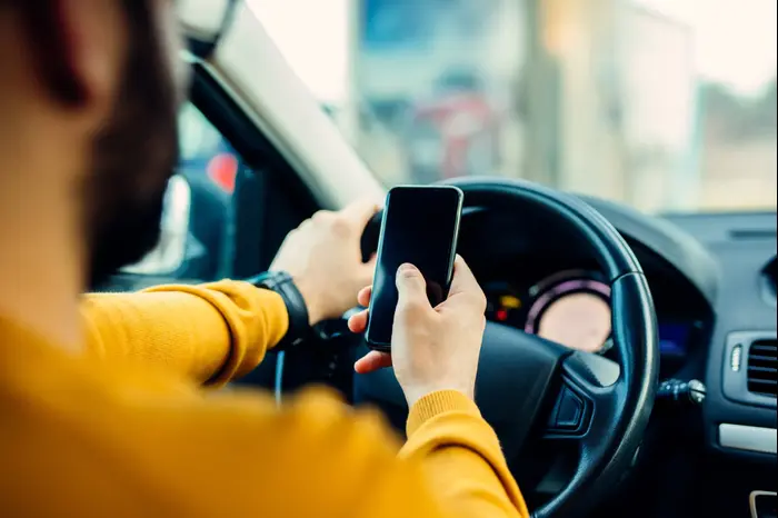נהג מתכתב בטלפון בזמן נהיגה (ShutterStock) נהג מתכתב בטלפון בזמן נהיגה (ShutterStock)