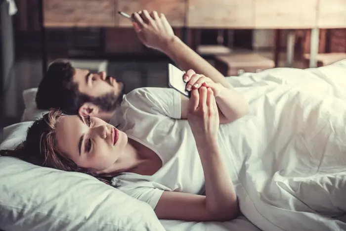 בני זוג במיטה עם טלפונים ניידים (ShutterStock) בני זוג במיטה עם טלפונים ניידים (ShutterStock)