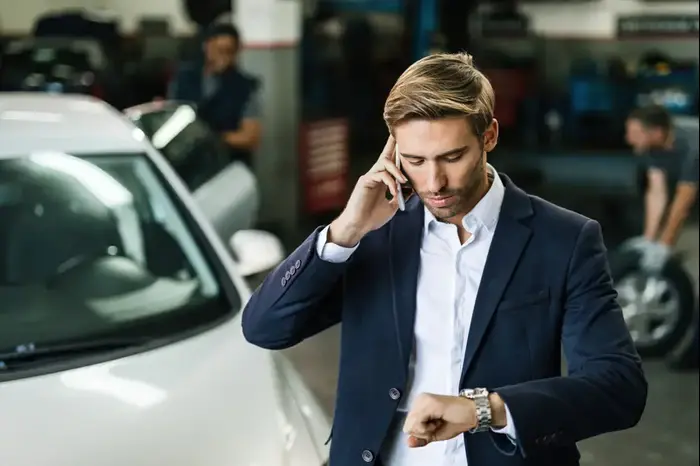 איש עסקים מציץ בשעונו בזמן היותו במוסך (ShutterStock) איש עסקים מציץ בשעונו בזמן היותו במוסך (ShutterStock)