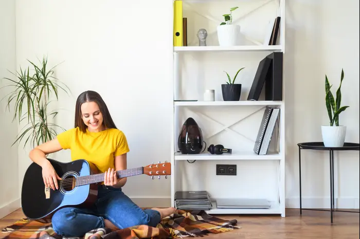 אישה צעירה מנגנת על גיטרה (ShutterStock) אישה צעירה מנגנת על גיטרה (ShutterStock)