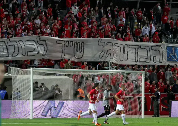 אוהדי הפועל תל אביב מניפים שלט באצטדיון בלומפילד (קובי אליהו) אוהדי הפועל תל אביב מניפים שלט באצטדיון בלומפילד (קובי אליהו)