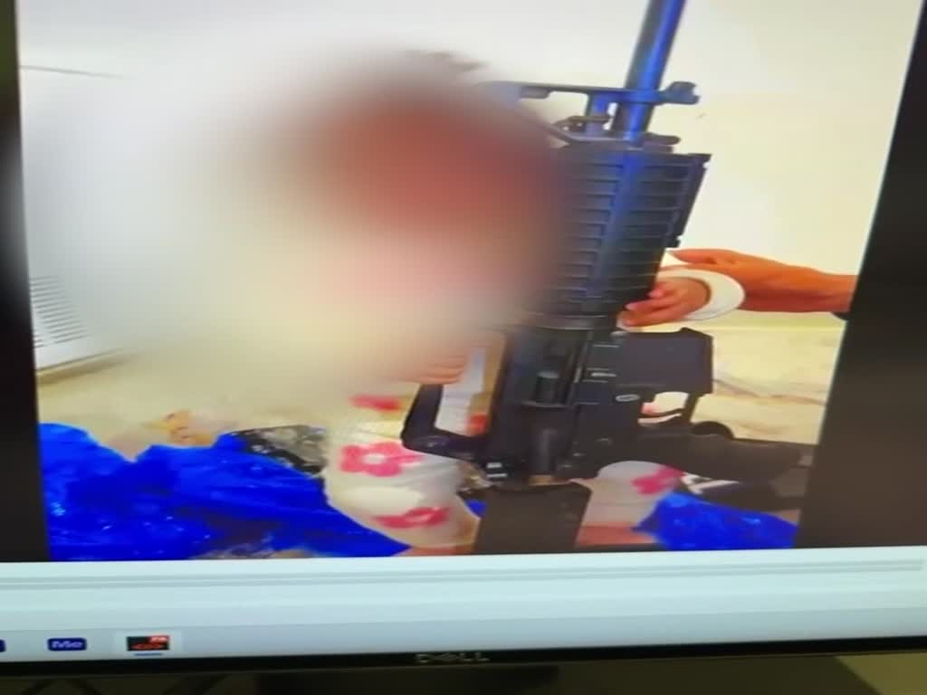 פעוטה משחקת בנשק מסוג M-16