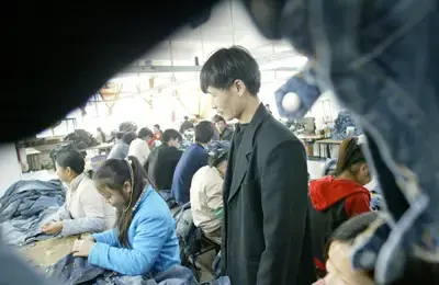 מפקח בסדנת היזע לייצור ג'ינס בסין. מתוך הסרט הדוקומנטרי China Blue, שסווג בסין כסרט אסור.