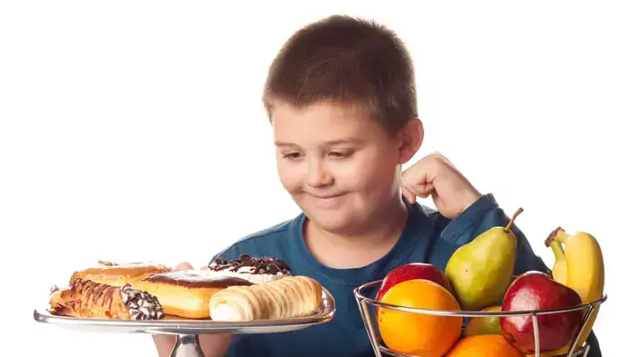 ילד עם עודף משקל מביט במזון ילד עם עודף משקל מביט במזון