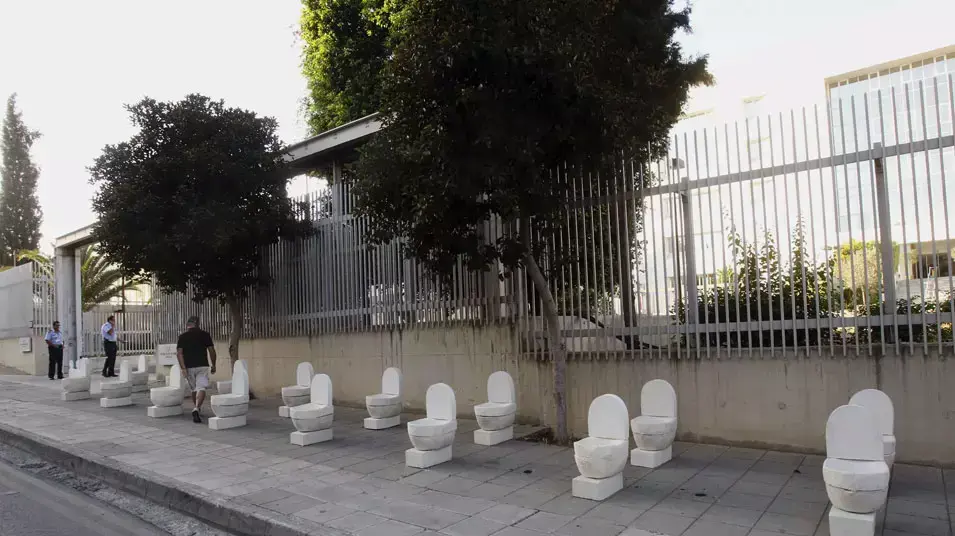 פסלים בצורת אסלות ומצבות שהוצבו כאקט מחאתי מול הבנק המרכזי בניקוסיה, קפריסין, 10 ביוני 2013 פסלים בצורת אסלות ומצבות שהוצבו כאקט מחאתי מול הבנק המרכזי בניקוסיה, קפריסין, 10 ביוני 2013