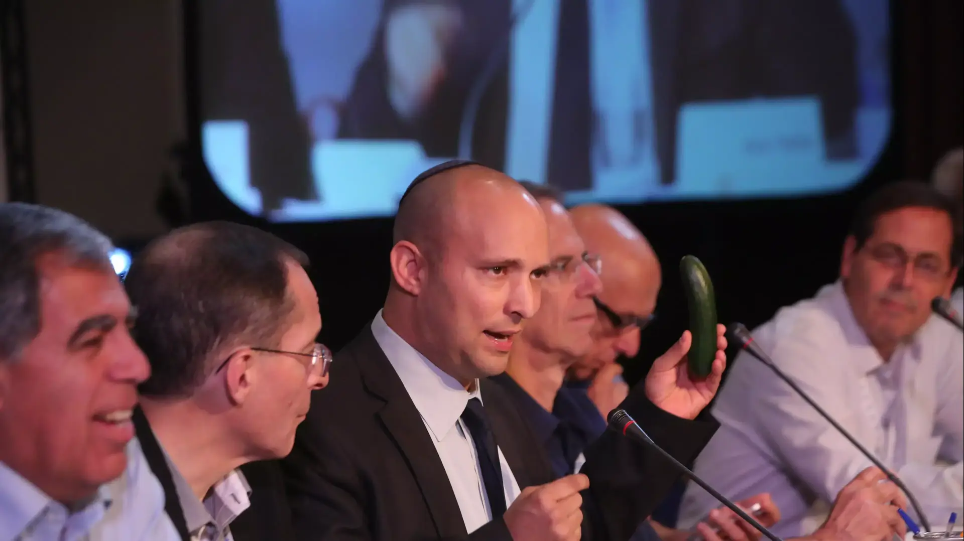שר הכלכלה נפתלי בנת שולף מלפפון בנאומו בפורום קיסריה. נובמבר 2013