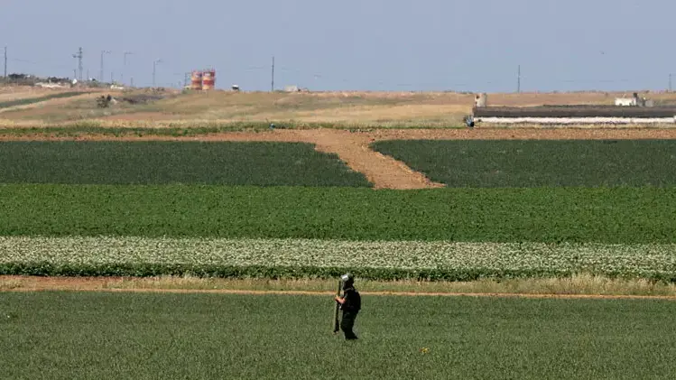 איש כוחות הביטחון מחזיק שרידי רקטה בשדות ליד קיבוץ נחל עוז, 2008 איש כוחות הביטחון מחזיק שרידי רקטה בשדות ליד קיבוץ נחל עוז, 2008