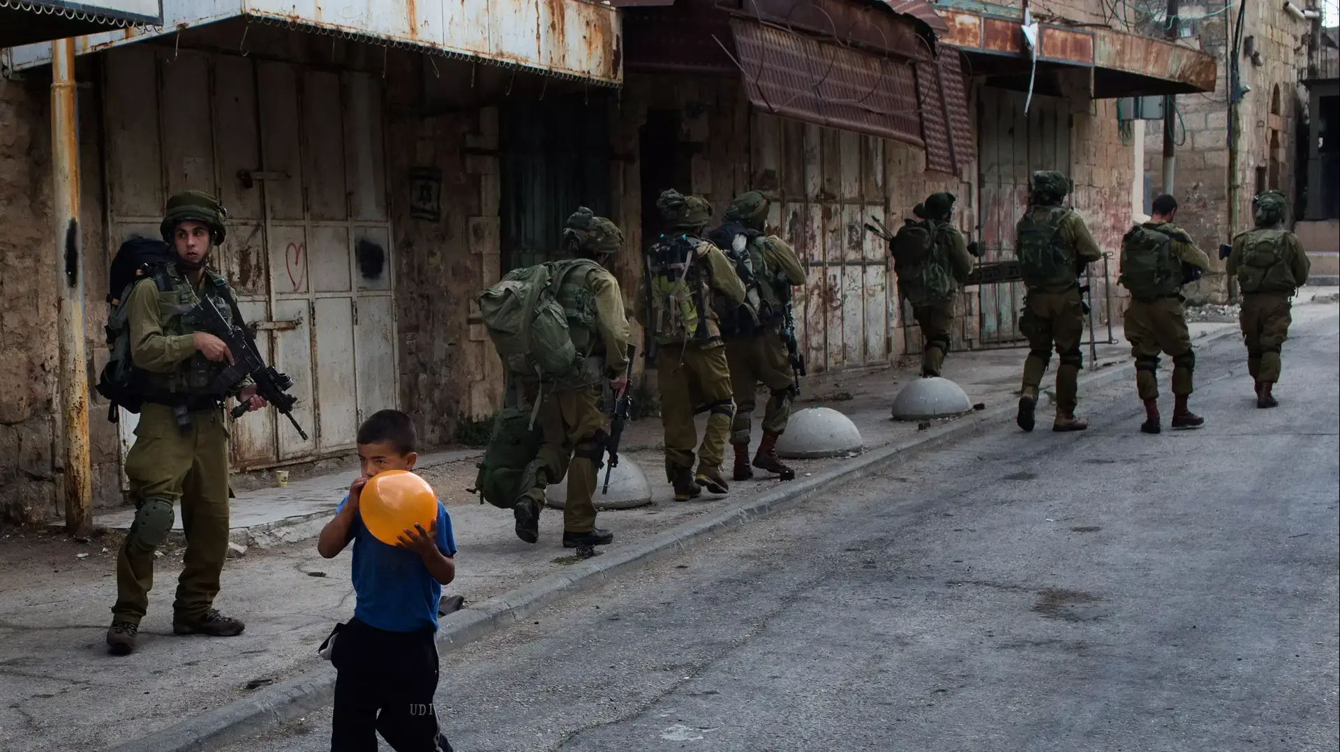 חיילי צה"ל ברחוב בחברון ולידם ילד מנפח בלון. ספטמבר 2013