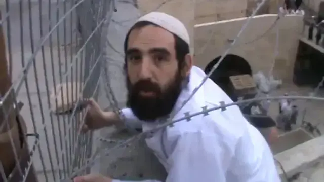 מתנחל ניסה להסיר דגל פלסטין  - ונתקע בגדר התיל