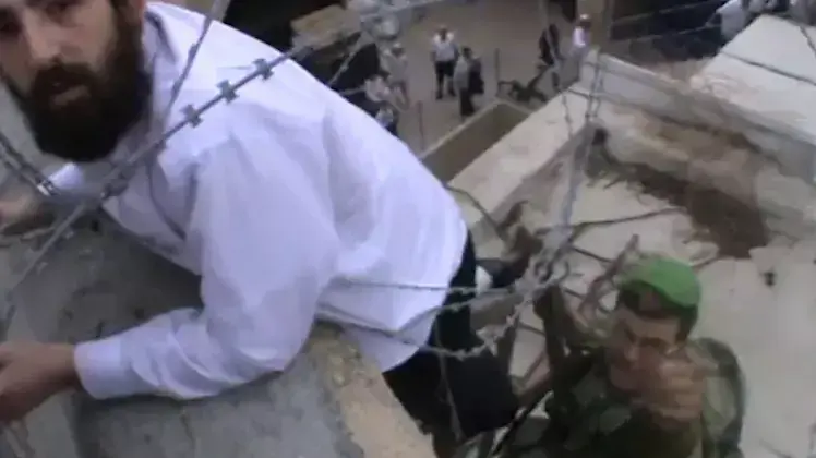 מתנחל נתקע בגדר תיל על גג בית בחברון בניסיון להסיר את גדלי הרשות הפלסטינית מתנחל נתקע בגדר תיל על גג בית בחברון בניסיון להסיר את גדלי הרשות הפלסטינית