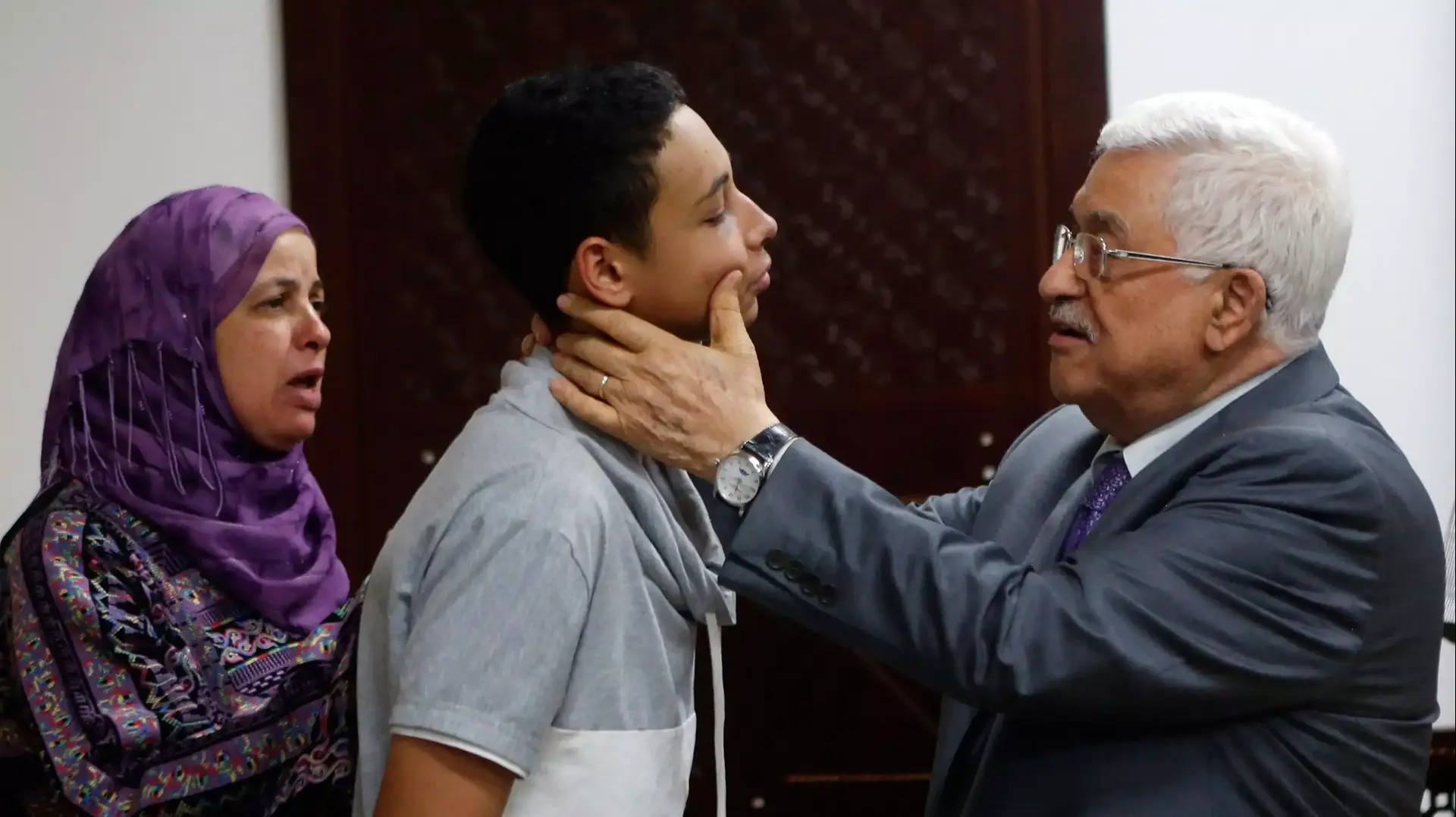 אבו מאזן בוחן את פניו של טארק אבו חדיר, בן דודו של הנער שנרצח, לאחר שהוכה בידי שוטרי מג"ב, יולי 2014