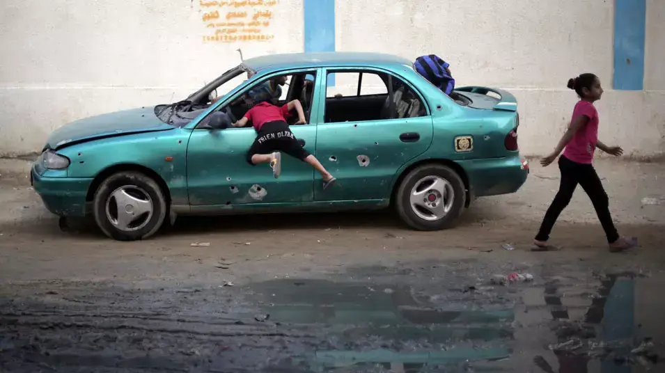 ילדים פלסטינים משחקים במכונית שנפגעה מתקיפת צה"ל ליד בית הספר של אונר"א, עזה. ספטמבר 2014 ילדים פלסטינים משחקים במכונית שנפגעה מתקיפת צה"ל ליד בית הספר של אונר"א, עזה. ספטמבר 2014