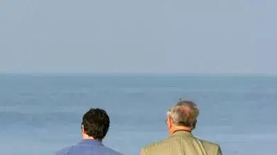אנשים מבוגרים הולכים על שפת הים יד ביד