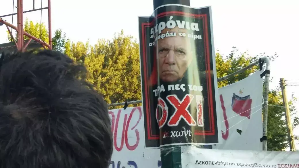 כרזה נגד שר החוץ של גרמניה וולפגנג שויבלה במהלך הפגנה של מחנה "הלא" באתונה, יוון, 3 ביולי 2015 כרזה נגד שר החוץ של גרמניה וולפגנג שויבלה במהלך הפגנה של מחנה "הלא" באתונה, יוון, 3 ביולי 2015