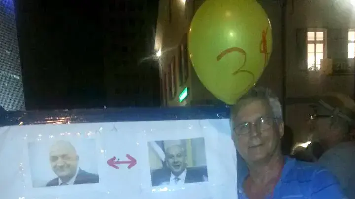 מפגין נושא שלט בהפגנה נגד מתווה הגז בתל אביב, 4 ביולי 2015