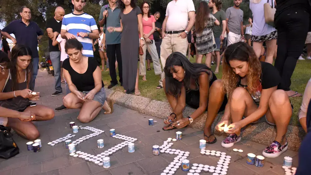 תומכים בעצרת המחאה השקטה לזכרו של גל בק מדליקים נרות, יולי 2015