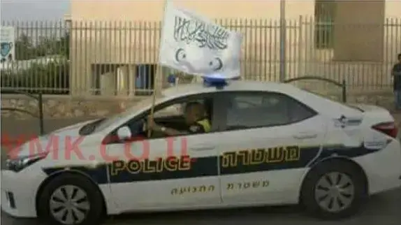שוטר בתוך ניידת מניף את דגל התנועה האיסלאמית, טובה זנגריה. 5 ביוני 2016 שוטר בתוך ניידת מניף את דגל התנועה האיסלאמית, טובה זנגריה. 5 ביוני 2016