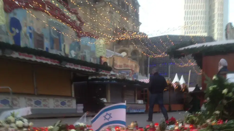 דגל ישראל בין נרות הזיכרון לזכר קורבנות פיגוע הדריסה בברלין, שוק חג המולד בברלין, 22 בדצמבר 2016