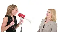 אישה מעבירה מסר לחברתה באמצעות מגאפון אישה מעבירה מסר לחברתה באמצעות מגאפון