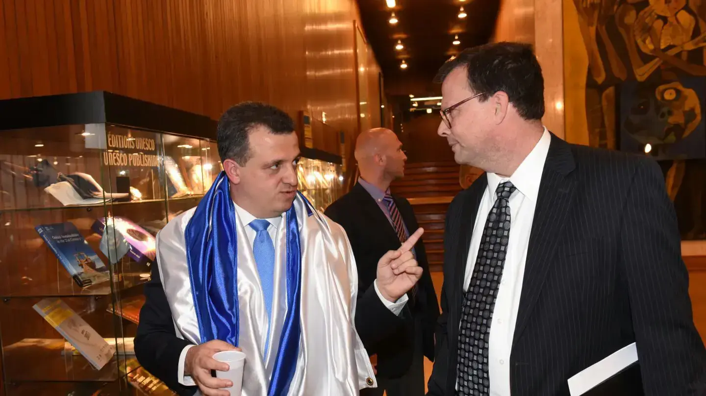 השגריר כרמל שאמה עוטה דגל ישראל היום בהצבעה, עם סגן השגריר האמריקאי 2 במאי 2017 השגריר כרמל שאמה עוטה דגל ישראל היום בהצבעה, עם סגן השגריר האמריקאי 2 במאי 2017