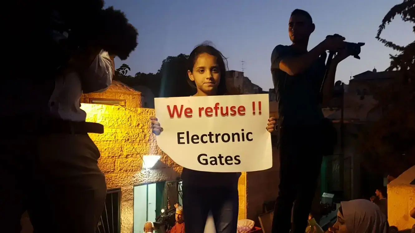 ילדה מחזיקה שלט במהלך תפילה המונית בכניסה האחורית של הר הבית, 19 ביולי 2017 ילדה מחזיקה שלט במהלך תפילה המונית בכניסה האחורית של הר הבית, 19 ביולי 2017