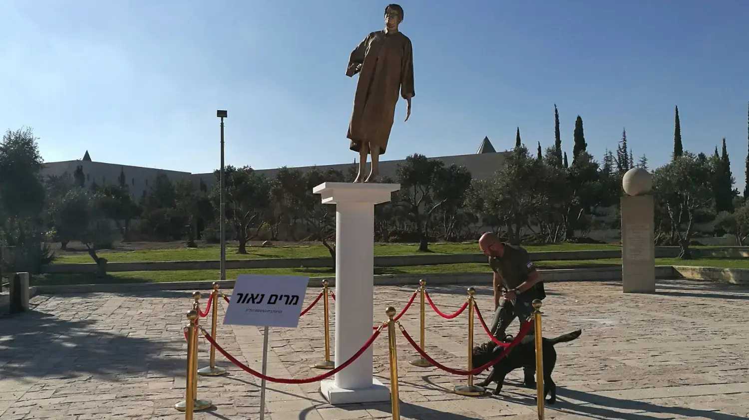 כלבן ליד פסל מוזהב של נשיאת בית המשפט העליון מרים נאור שהוצב מחוץ לבג"ץ, 31 באוגוסט 2017 כלבן ליד פסל מוזהב של נשיאת בית המשפט העליון מרים נאור שהוצב מחוץ לבג"ץ, 31 באוגוסט 2017