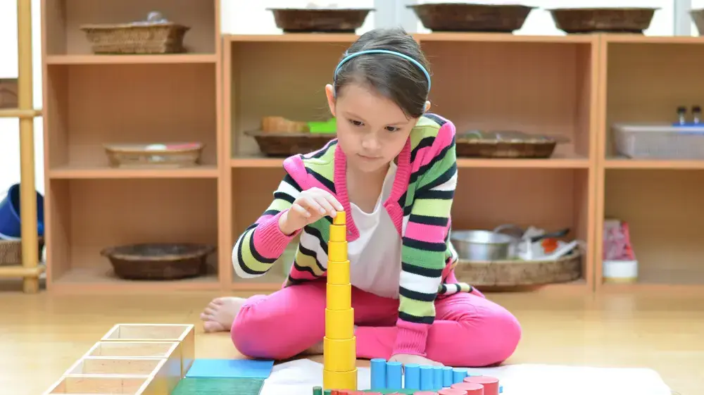 ילדה משחקת בצעצועי עץ על שטיחון בחדר משחקים ילדה משחקת בצעצועי עץ על שטיחון בחדר משחקים