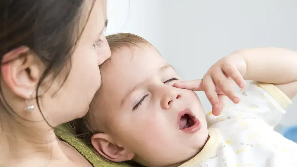 אמא מנשקת תינוק חולה עם אף סתום אמא מנשקת תינוק חולה עם אף סתום