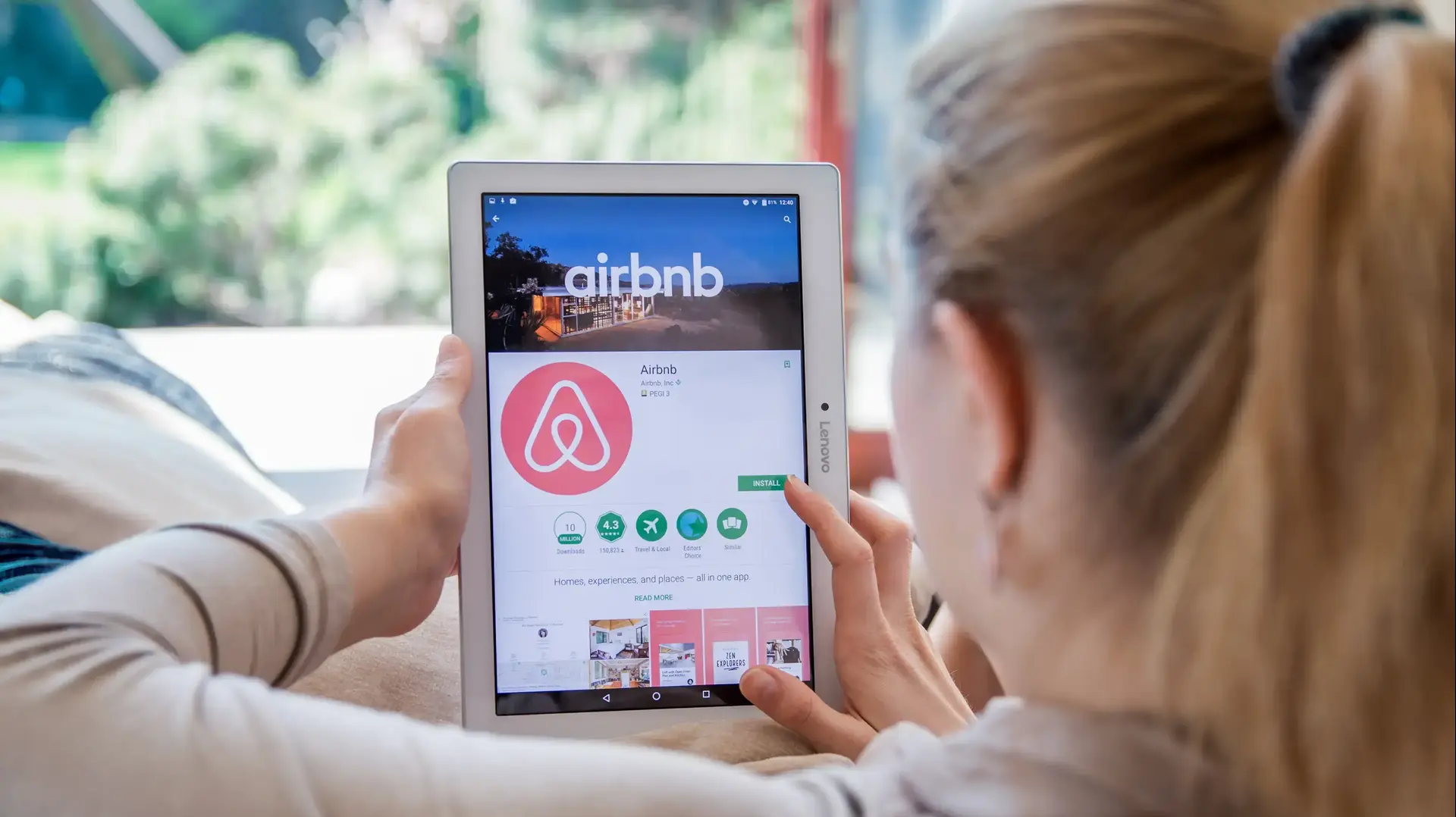 אישה גולשת באתר Airbnb באמצעות טאבלט אישה גולשת באתר Airbnb באמצעות טאבלט