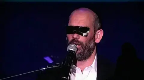 הזמר והיוצר יונתן רזאל מופיע בפני נשים עם מסנטייפ על עיניו הזמר והיוצר יונתן רזאל מופיע בפני נשים עם מסנטייפ על עיניו