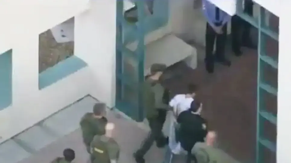 החשוד בירי בתיכון בפלורידה, ארה"ב, מלווה על ידי שוטרים מבית החולים, 14 בפברואר 2018 החשוד בירי בתיכון בפלורידה, ארה"ב, מלווה על ידי שוטרים מבית החולים, 14 בפברואר 2018