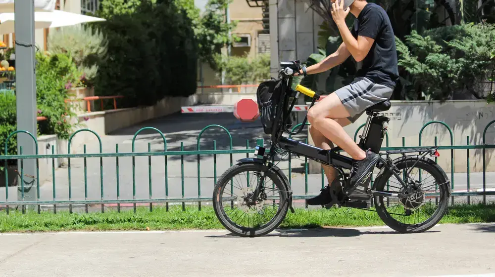 בחור רוכב על אופניים חשמליים בשדרות רוטשילד, תל אביב בחור רוכב על אופניים חשמליים בשדרות רוטשילד, תל אביב