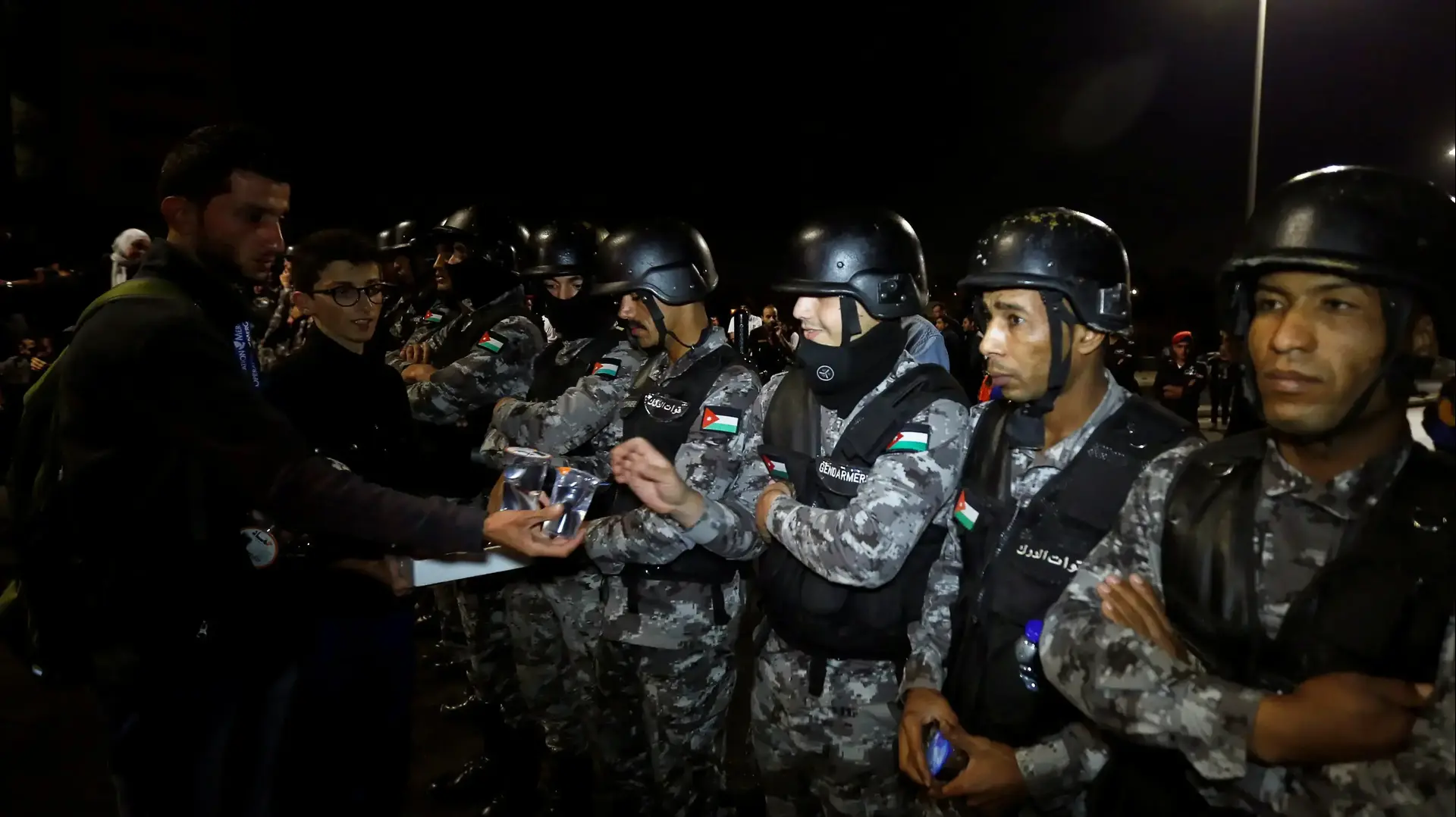 מפגינים בעמאן בירת ירדן שמחו נגד העלאת מסים ומדיניות הצנע של הממשלה מציעים לשוטרים המאבטחים אותם מים ותמרים, 5 ביוני 2018 מפגינים בעמאן בירת ירדן שמחו נגד העלאת מסים ומדיניות הצנע של הממשלה מציעים לשוטרים המאבטחים אותם מים ותמרים, 5 ביוני 2018