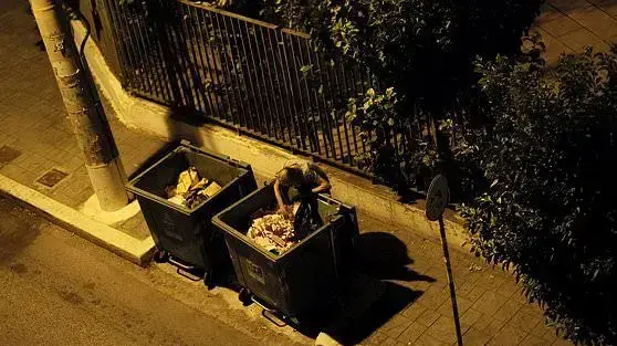 איש מחפש מזון בפח אשפה בשכונת טאברוס, באתונה, יוון, 16 באוגוסט 2018 איש מחפש מזון בפח אשפה בשכונת טאברוס, באתונה, יוון, 16 באוגוסט 2018